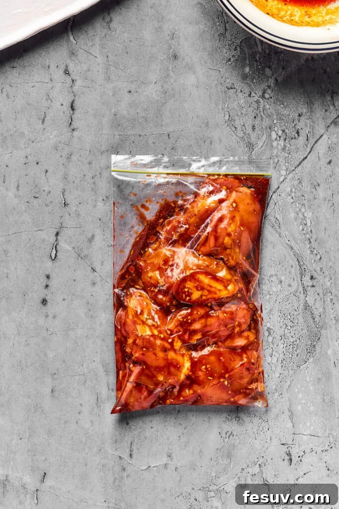 Boneless, skinless chicken thighs marinating in a sealed zip-top bag, ensuring even coating of the marinade.