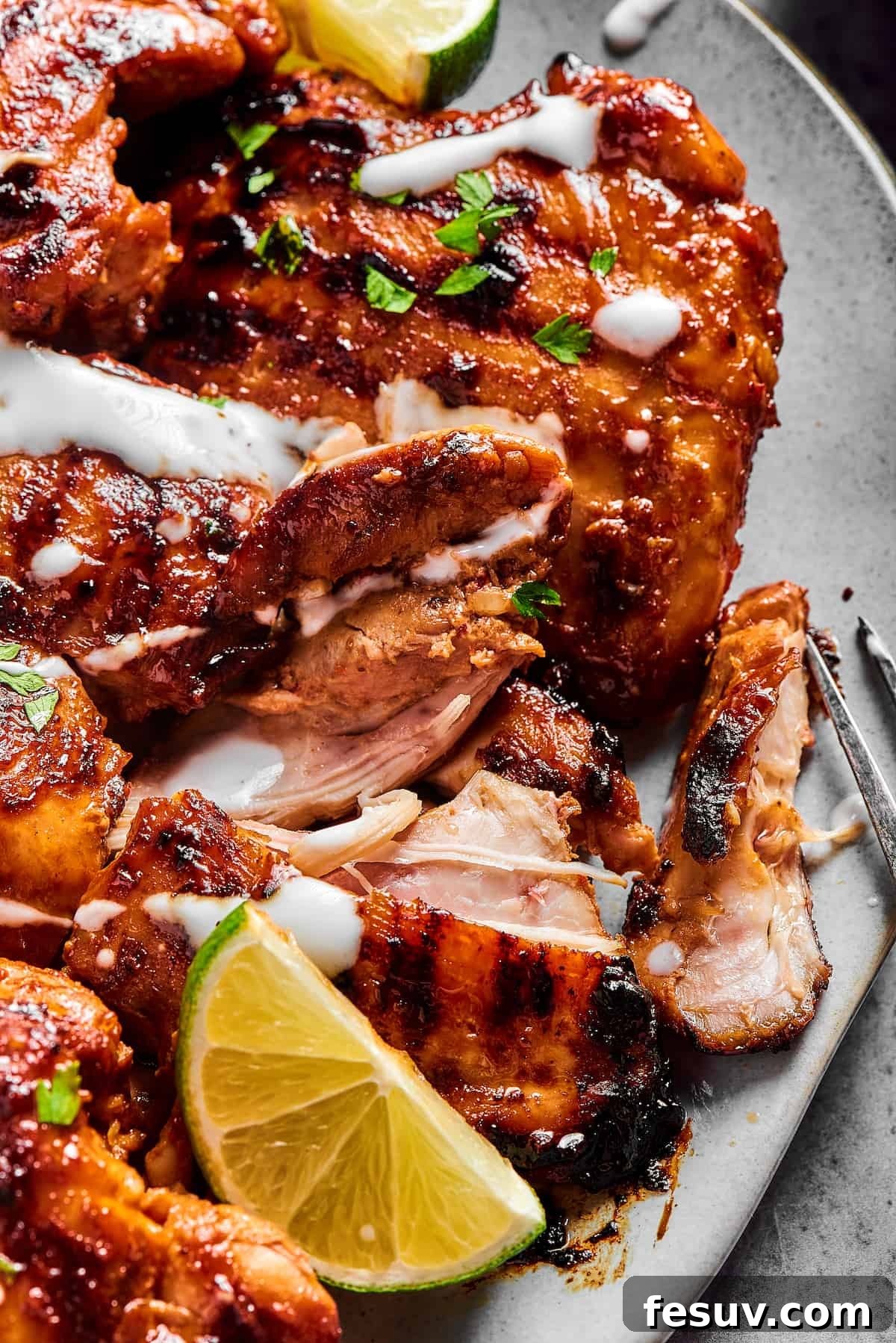 A single serving of grilled chicken on a white plate, elegantly garnished with fresh herbs and a swirl of creamy yogurt.
