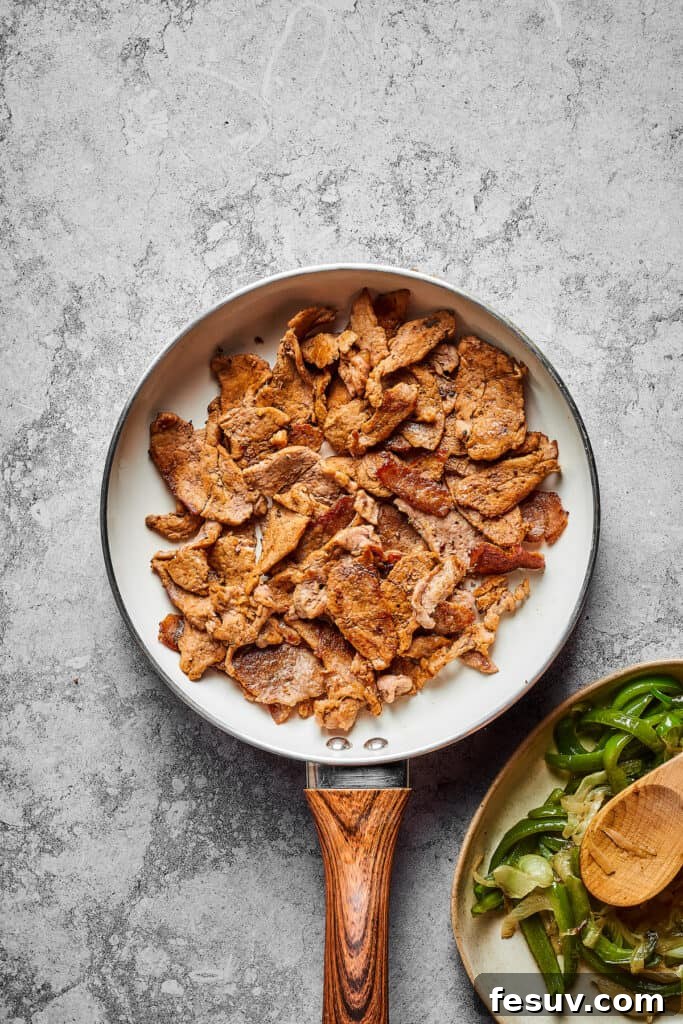 Steak strips cooking in a skillet.