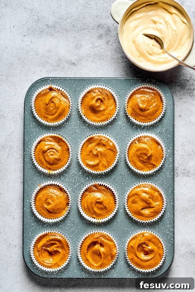 Cream Cheese Swirl Pumpkin Muffins 5 A muffin tin with muffin batter poured into paper liners.