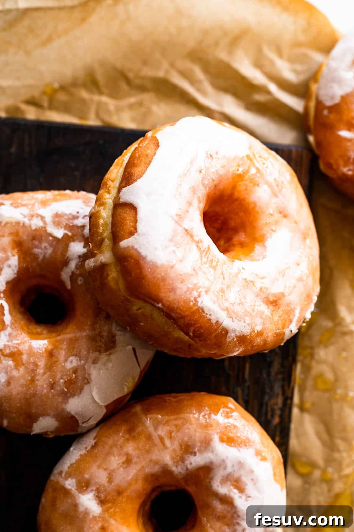 Beautifully glazed apple cider doughnuts resting on a rustic wooden board, ready to be enjoyed.