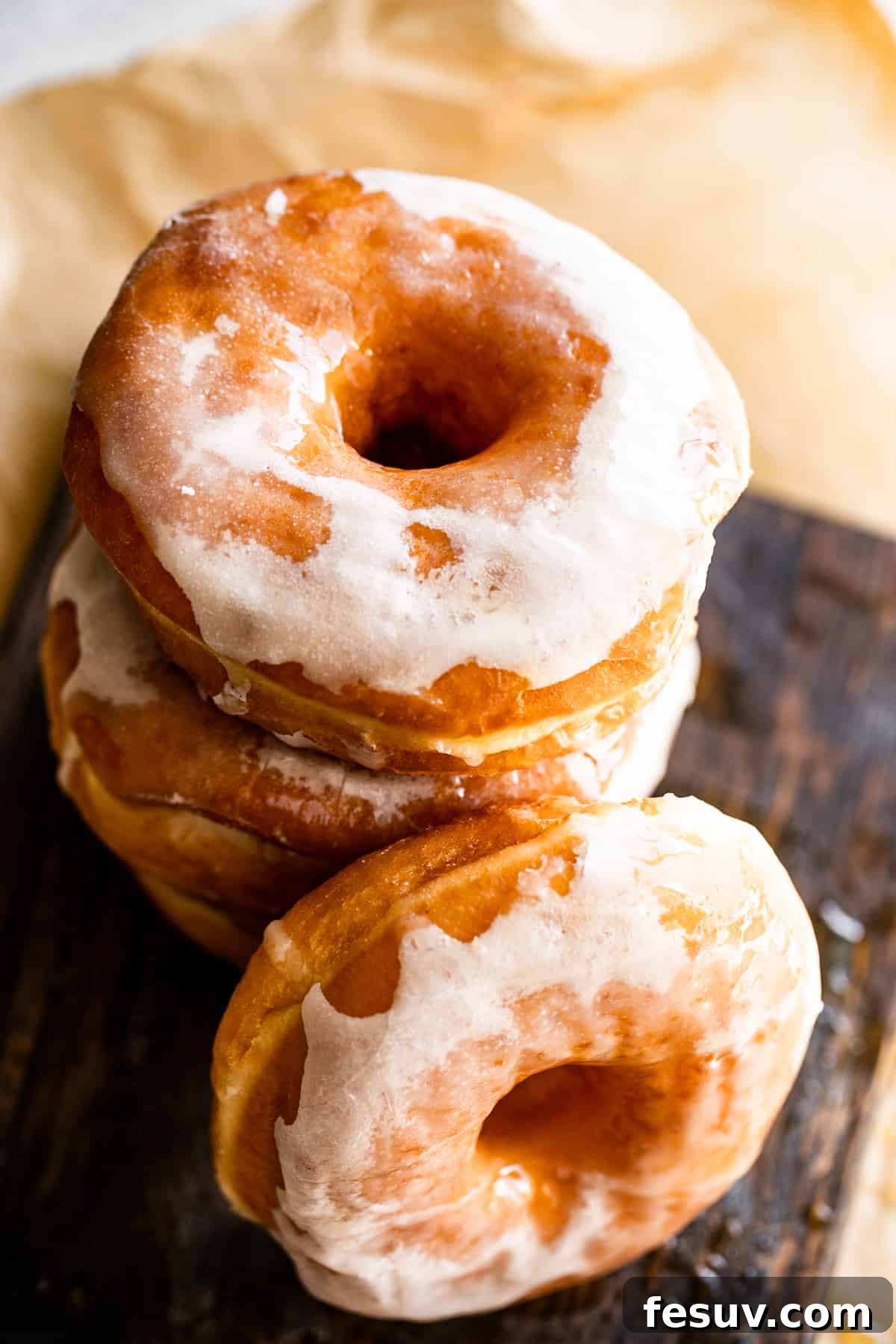 An inviting overhead shot of perfectly stacked baked doughnuts set against a cozy brown backdrop.