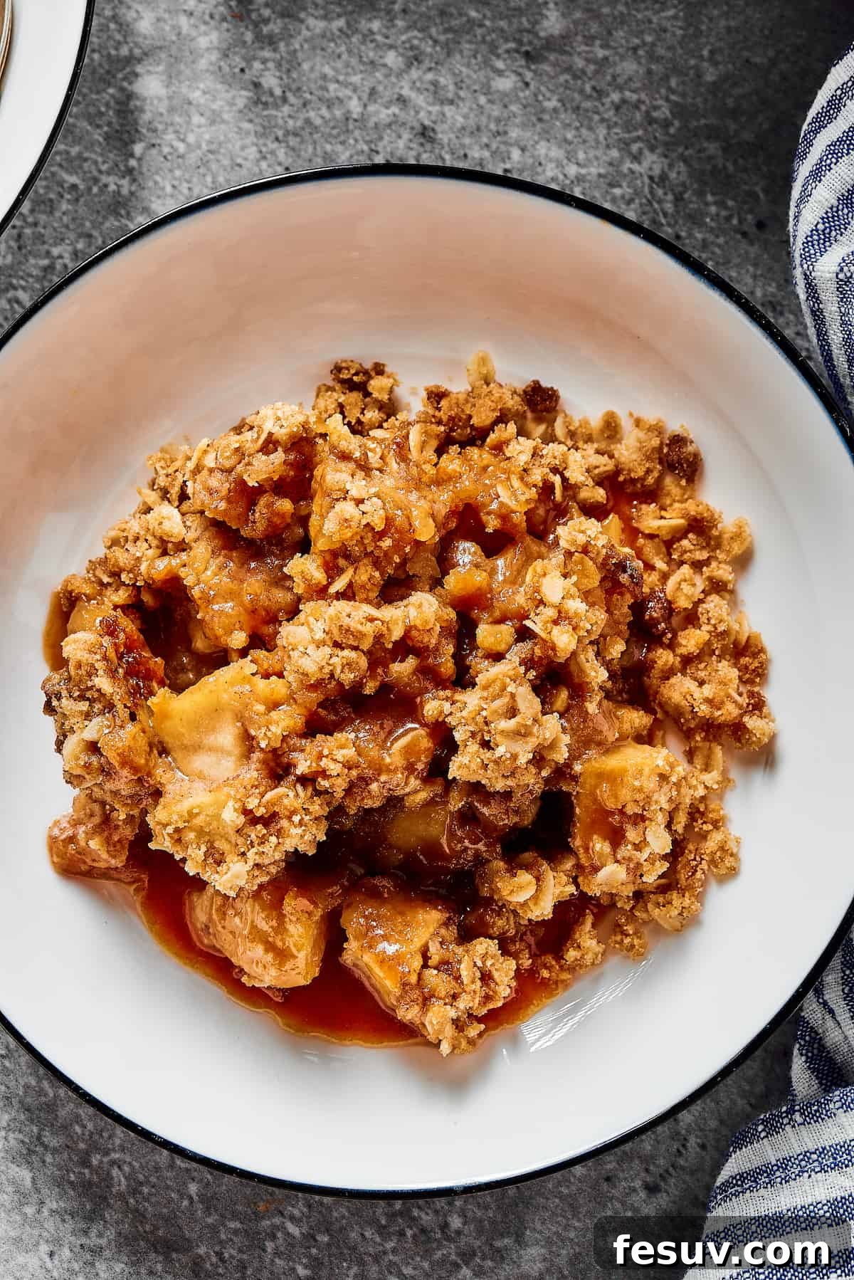 An overhead shot of a freshly baked apple crisp in a casserole dish, showing the golden-brown oat topping with hints of bubbling apple filling around the edges.