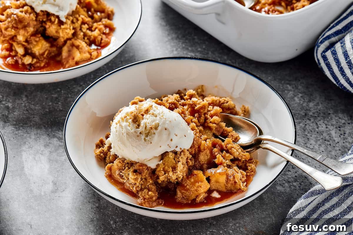 Warm apple crisp à la mode, served in individual dessert plates, topped with a generous scoop of vanilla ice cream and a drizzle of caramel sauce.
