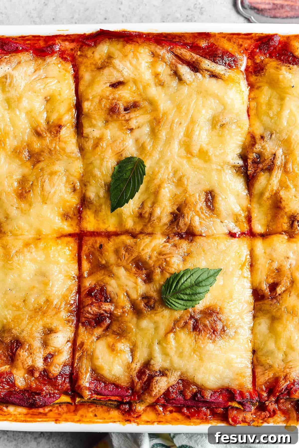 A close-up of a pan of freshly baked Zucchini Lasagna, neatly cut into large, appealing squares, ready to be served.