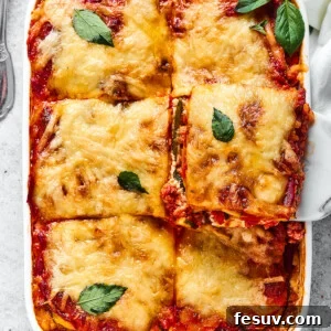 A comforting Zucchini Lasagna with rich meat sauce being served from a white rectangular baking dish, showcasing golden-brown cheese and tender zucchini layers.
