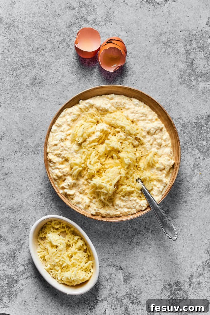 Adding shredded mozzarella cheese to the rich cottage cheese and egg mixture for the lasagna's creamy filling.