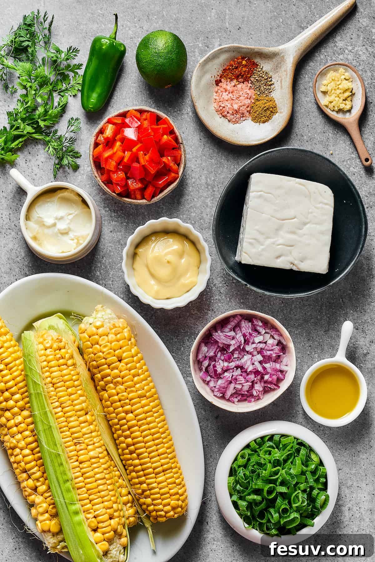 Mexican Street Corn Salad is a mouthwatering dish that’ll have everyone begging for the recipe! Fresh corn kernels in a killer creamy sauce. Assortment of fresh ingredients for Mexican Street Corn Salad, including corn, bell pepper, jalapeno, cilantro, cheeses, and sauces.