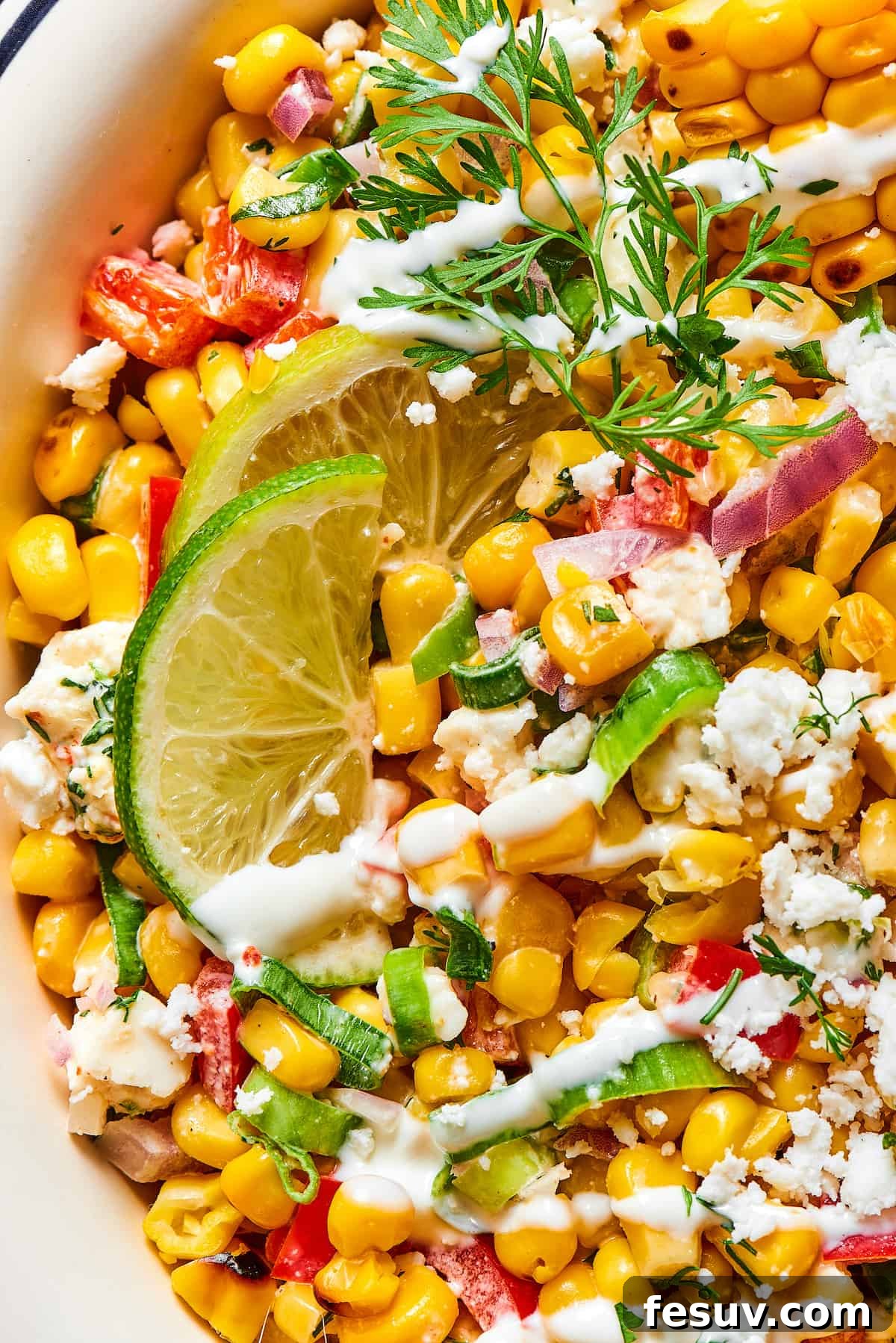 Mexican Street Corn Salad is a mouthwatering dish that’ll have everyone begging for the recipe! Fresh corn kernels in a killer creamy sauce. Close-up shot of Mexican street corn salad, showing the texture of the ingredients and the dressing.