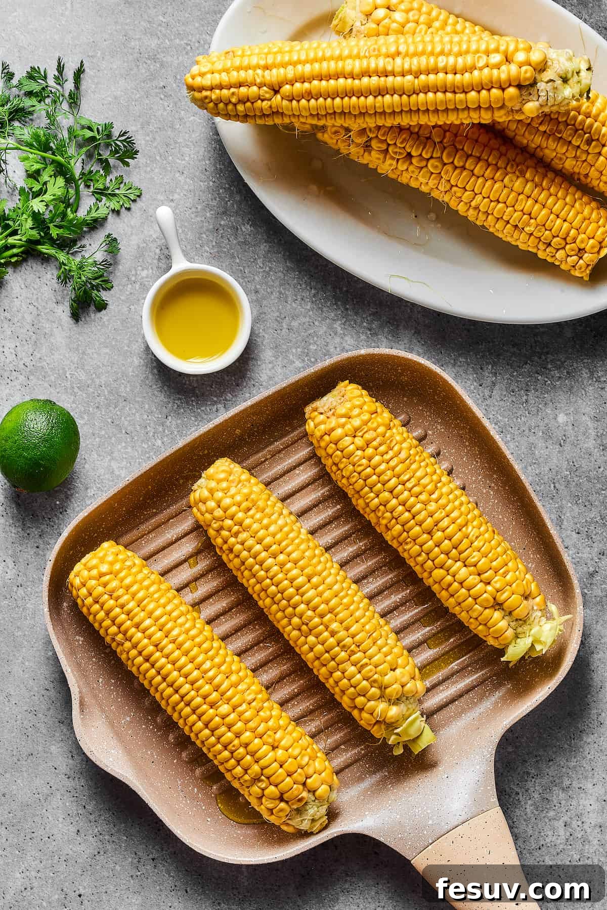 Mexican Street Corn Salad is a mouthwatering dish that’ll have everyone begging for the recipe! Fresh corn kernels in a killer creamy sauce. Ears of corn cooking on a grill pan, showing grill marks.