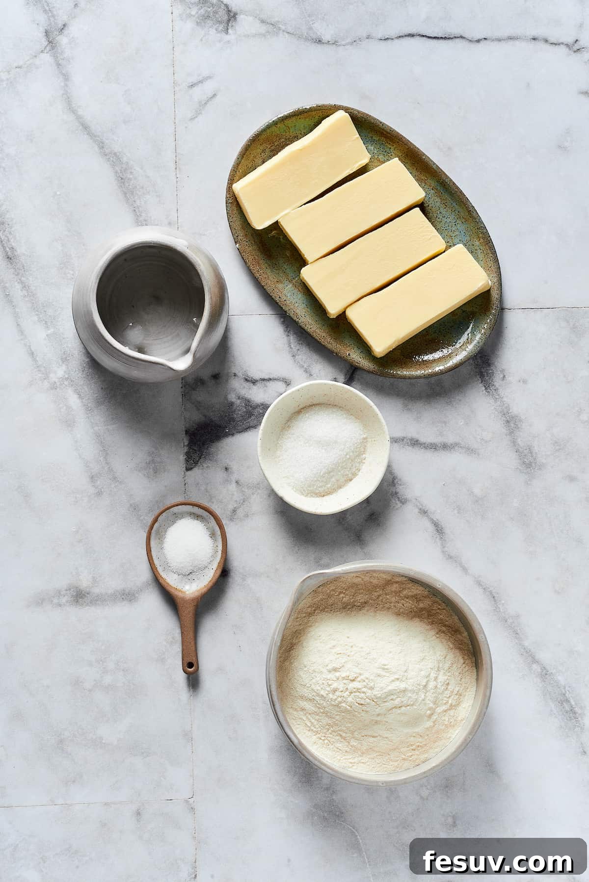 Individual ingredients for pie crust: diced cold butter, flour, sugar, salt, and ice water.