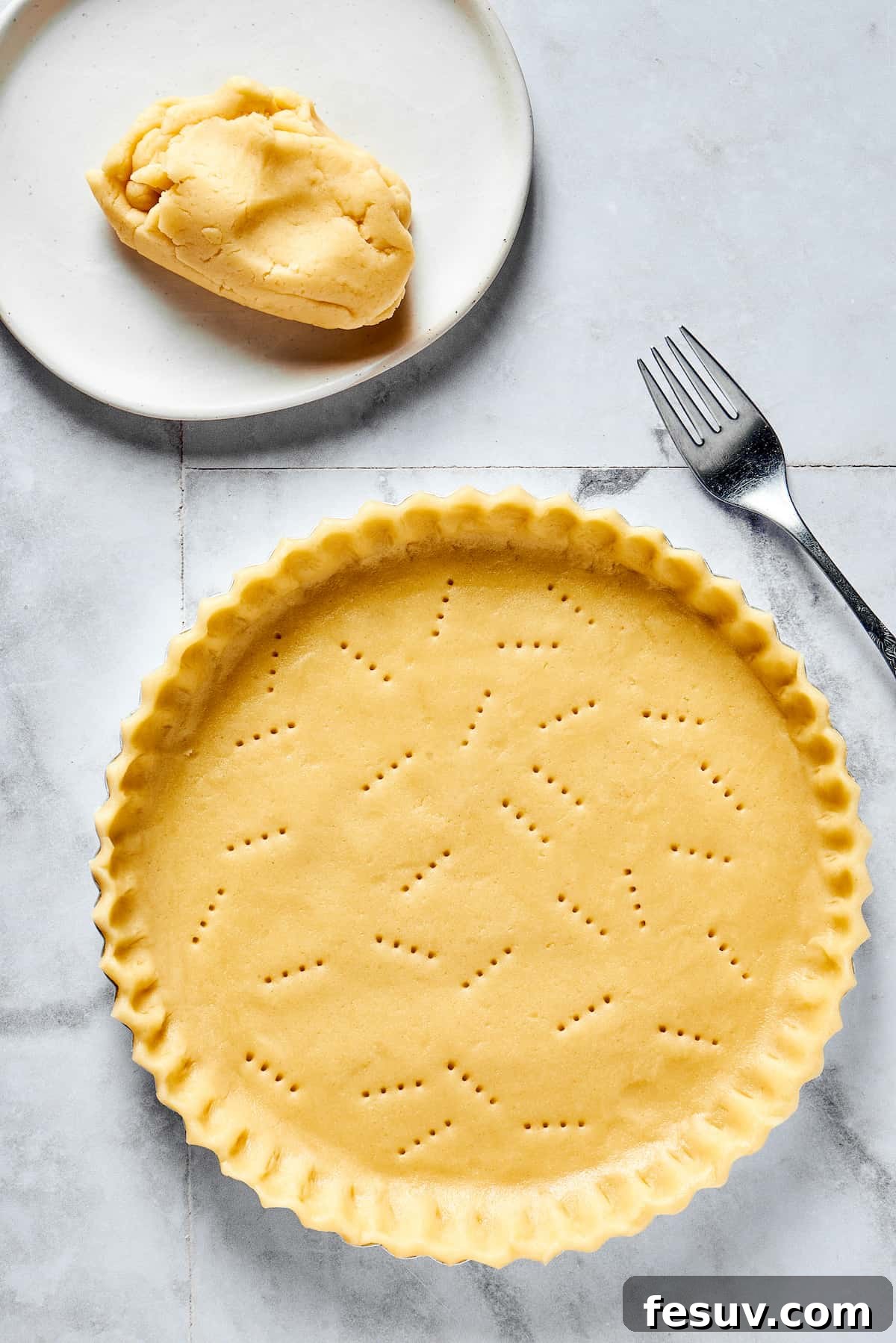 A pie crust neatly pressed into a pie dish, with crimped edges and fork pricks on the bottom.