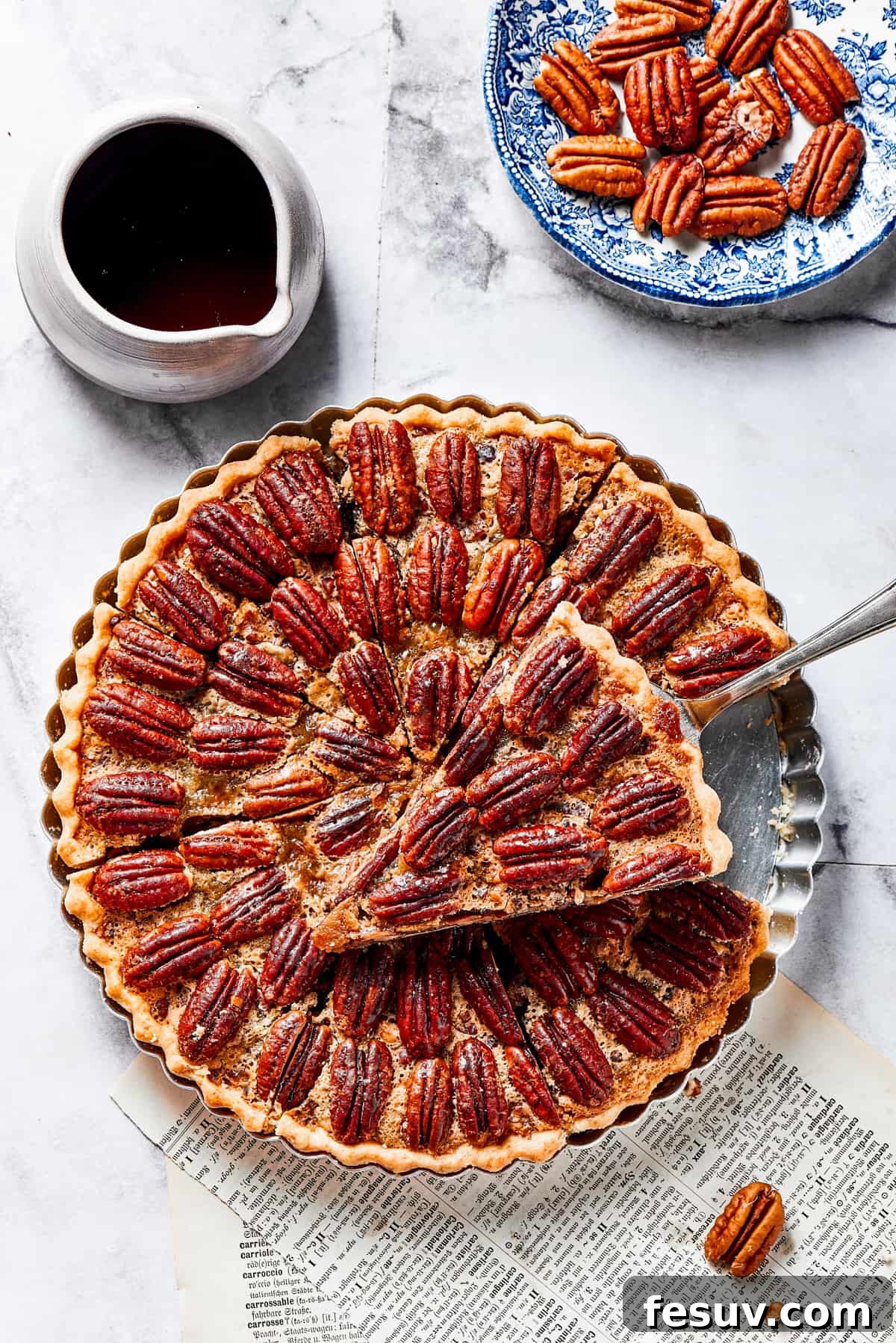 The Best Pecan Pie Recipe is here, easy to make and perfect for your holiday table! You'll love the homemade crust and sweet, nutty filling. A slice of pie on a pie server, held just above the rest of the pie.