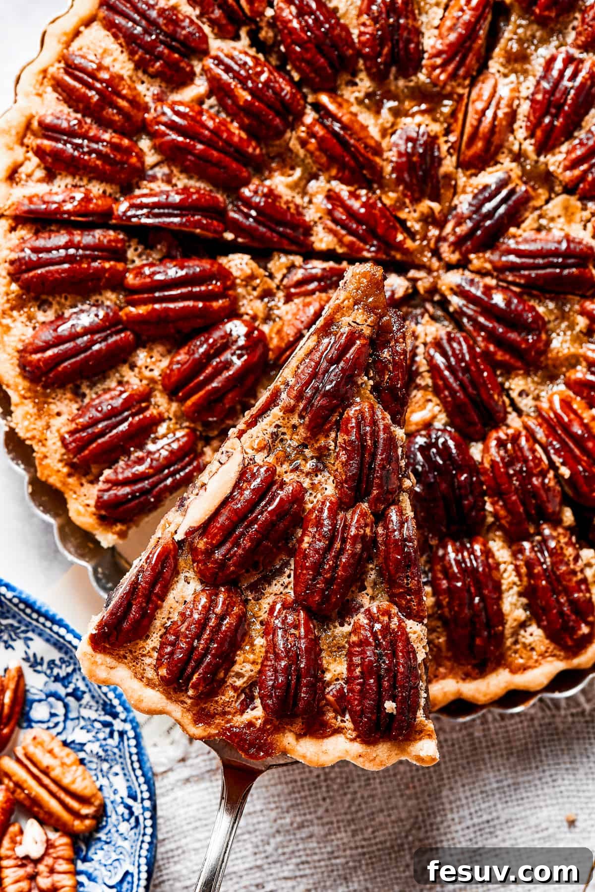 The Best Pecan Pie Recipe is here, easy to make and perfect for your holiday table! You'll love the homemade crust and sweet, nutty filling. Close-up shot of a slice of pie being lifted out of the pan.