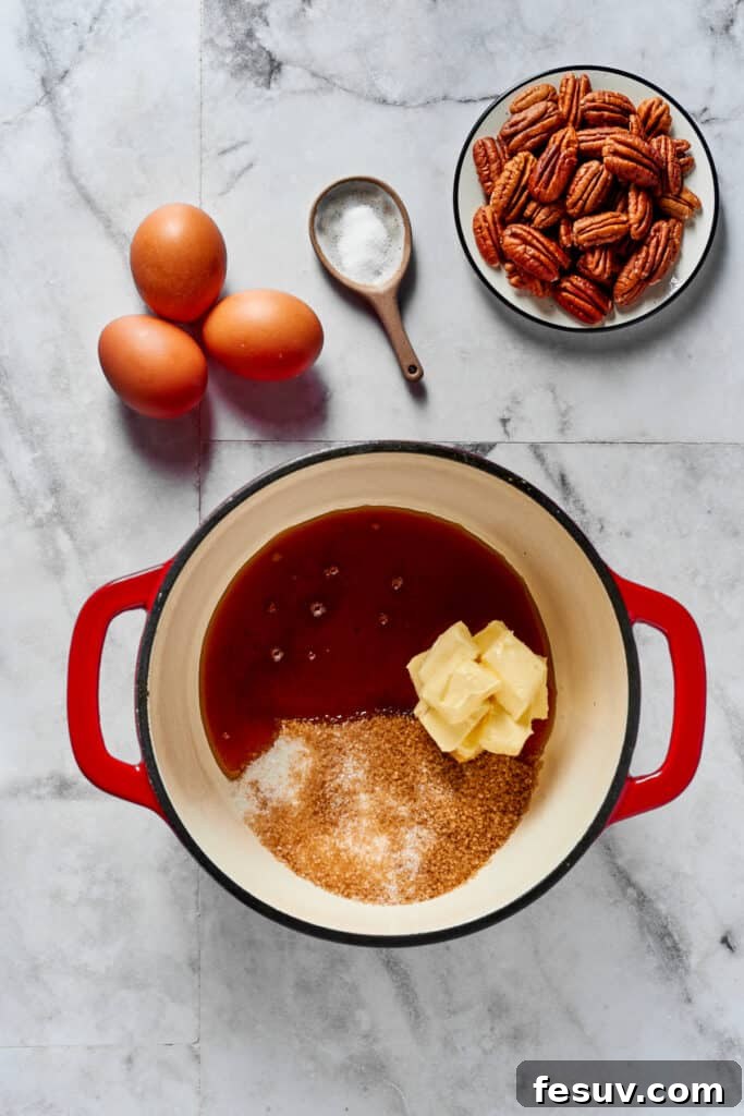 Decadent Pecan Pie Perfection 2 A heavy pot with butter, sugar, and syrup inside. Eggs, salt, an pecans are arranged in dishes on the work surface.