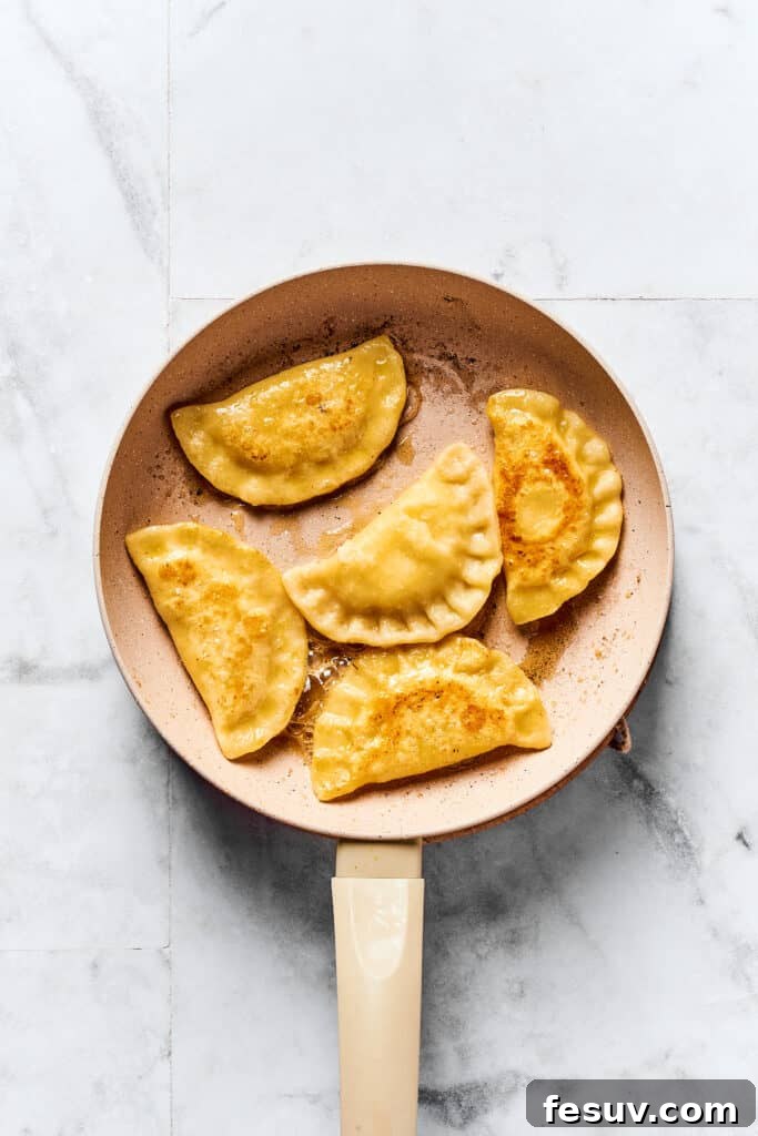 Handcrafted Pierogi Delights 9 A skillet full of pierogies frying in butter until golden brown.