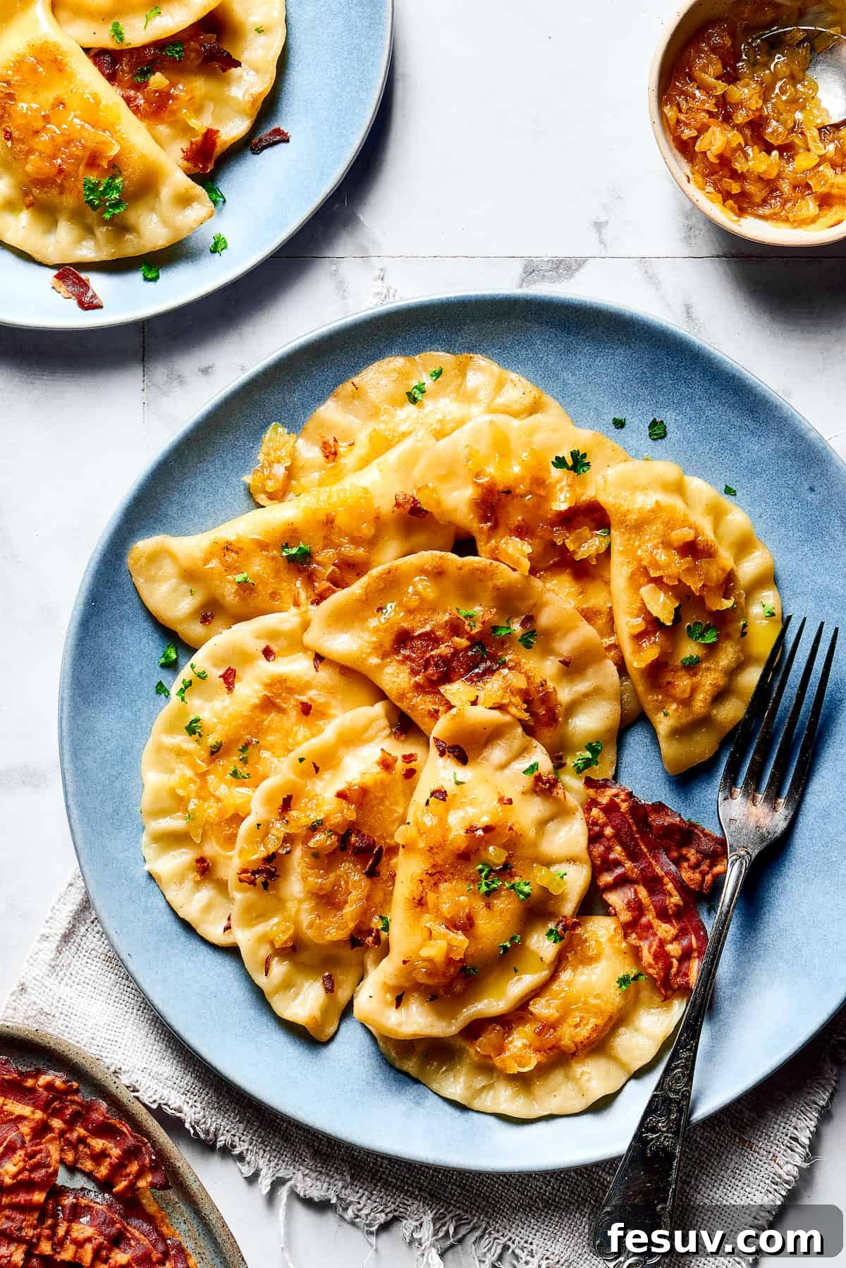 Topped with caramelized onion and crispy bacon, this easy Homemade Pierogi Recipe features a traditional cheese and potato filling. Yum! Cooked pierogi topped with a generous amount of crispy bacon and perfectly caramelized onions, ready to be served.
