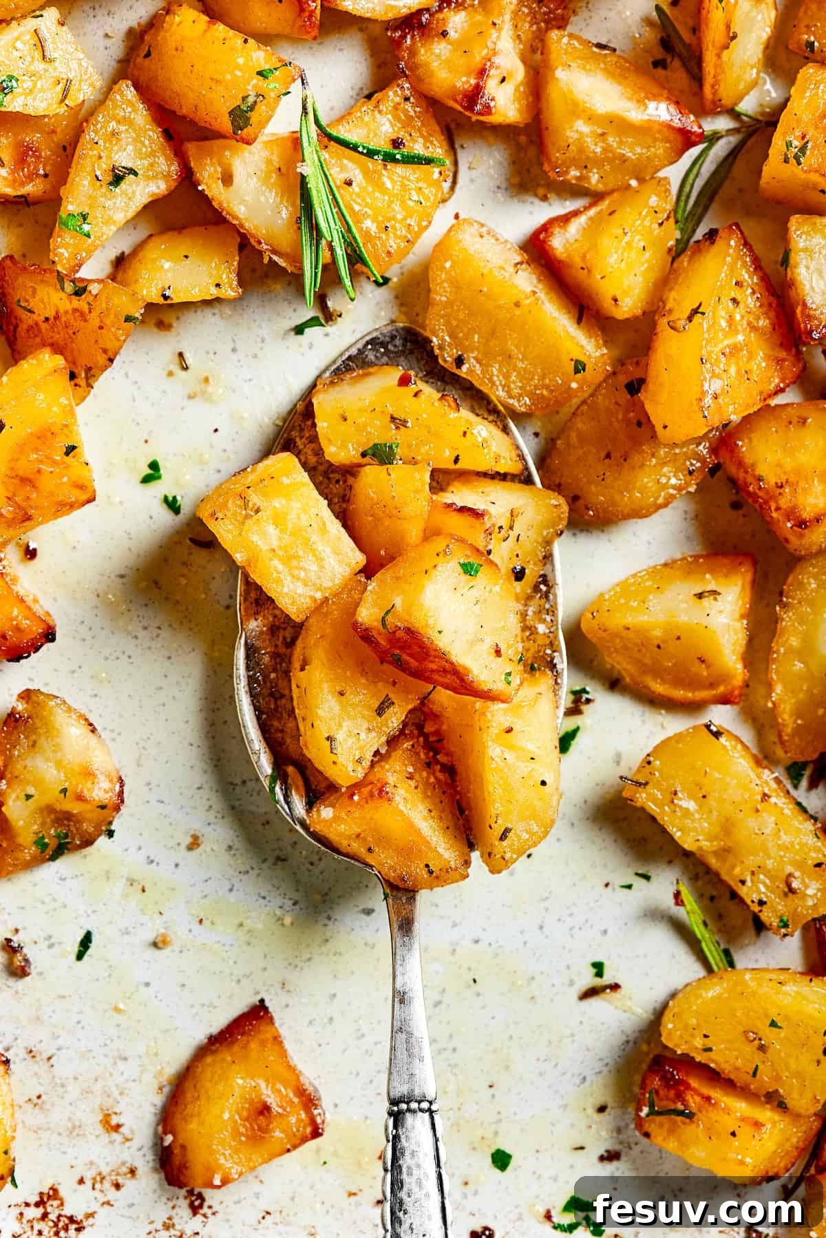 ed Potatoes are crisp, buttery, and easy to make. With a simple seasoning of salt, pepper, and rosemary, they're irresistible! A tray of roast potatoes with a silver spoon lifting some of the potato pieces.