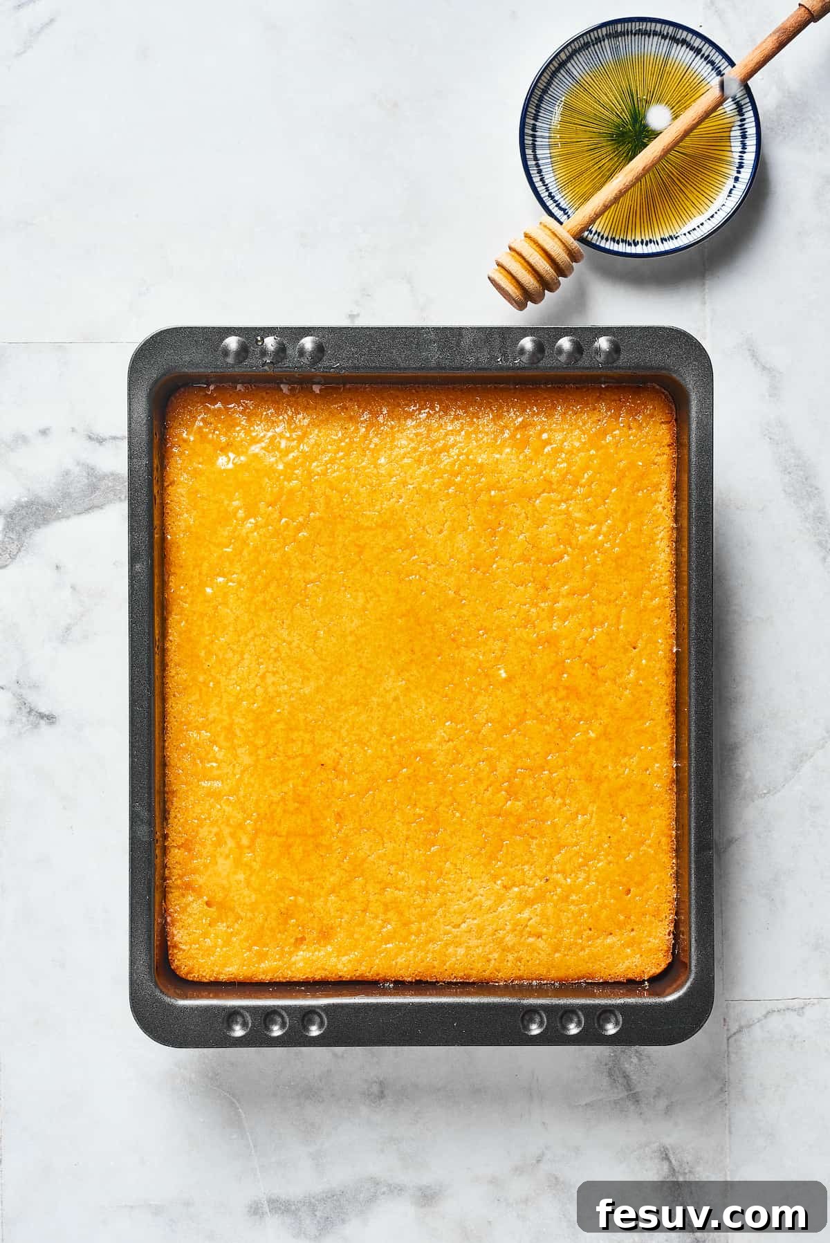 A freshly baked loaf of golden cornbread rests in a ceramic baking dish, ready to be sliced and served, showcasing its inviting crust.
