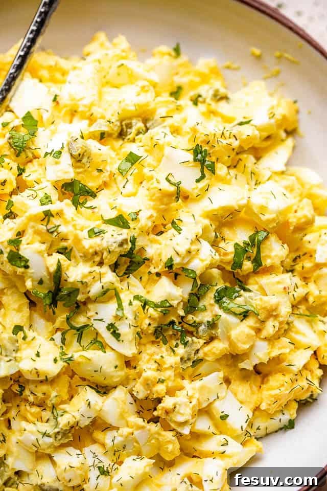 egg salad in a bowl topped with fresh parsley