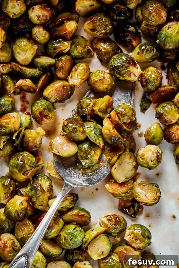 Crispy Brussels Perfection 7 Tossing roasted Brussels sprouts with the glistening maple-pomegranate glaze on a baking sheet.