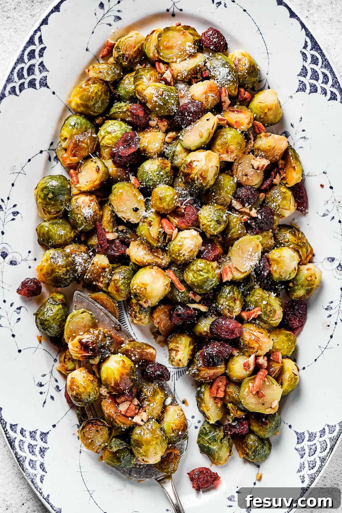 These Roasted Brussels Sprouts are oven-roasted with garlic and drizzled with a killer maple-pomegranate glaze. A veggie side you’ll crave! A close-up shot of perfectly glazed Brussels sprouts, garnished with bright red cranberries and crunchy pecans.