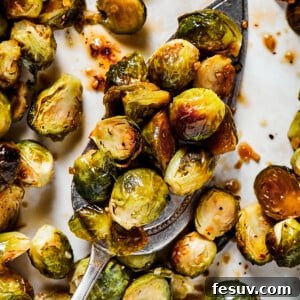 A tray of roasted brussel sprouts with a silver serving spoon.
