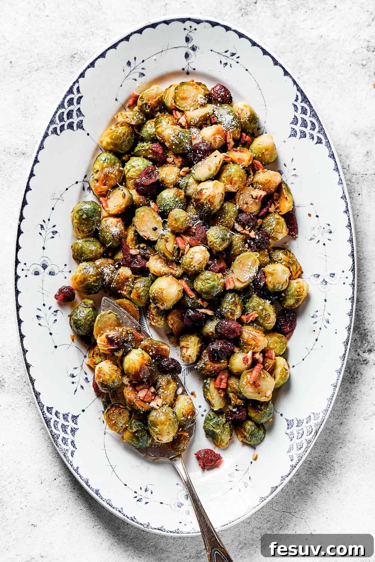 These Roasted Brussels Sprouts are oven-roasted with garlic and drizzled with a killer maple-pomegranate glaze. A veggie side you’ll crave! An oval platter overflowing with beautifully roasted, glazed Brussels sprouts.
