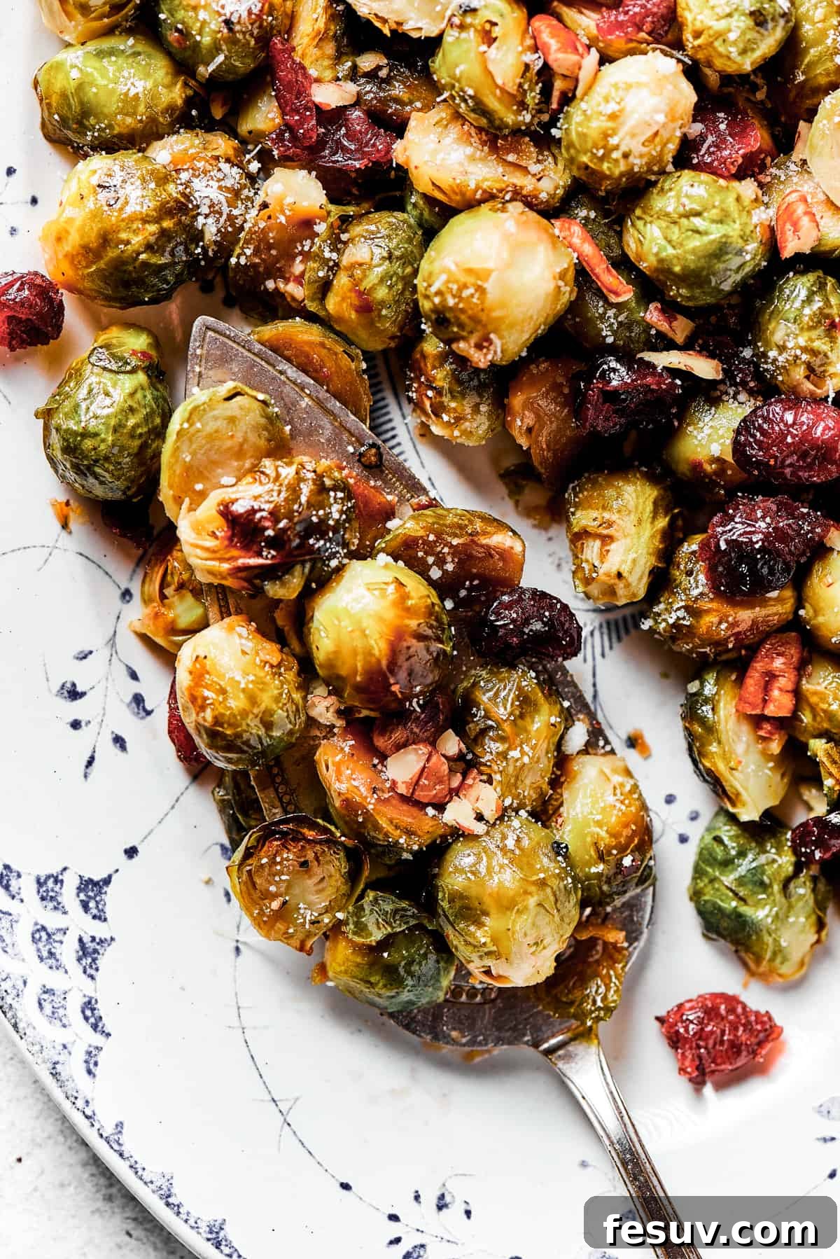 These Roasted Brussels Sprouts are oven-roasted with garlic and drizzled with a killer maple-pomegranate glaze. A veggie side you’ll crave! A large serving platter loaded with golden brown roasted Brussels sprouts, ready to be enjoyed.
