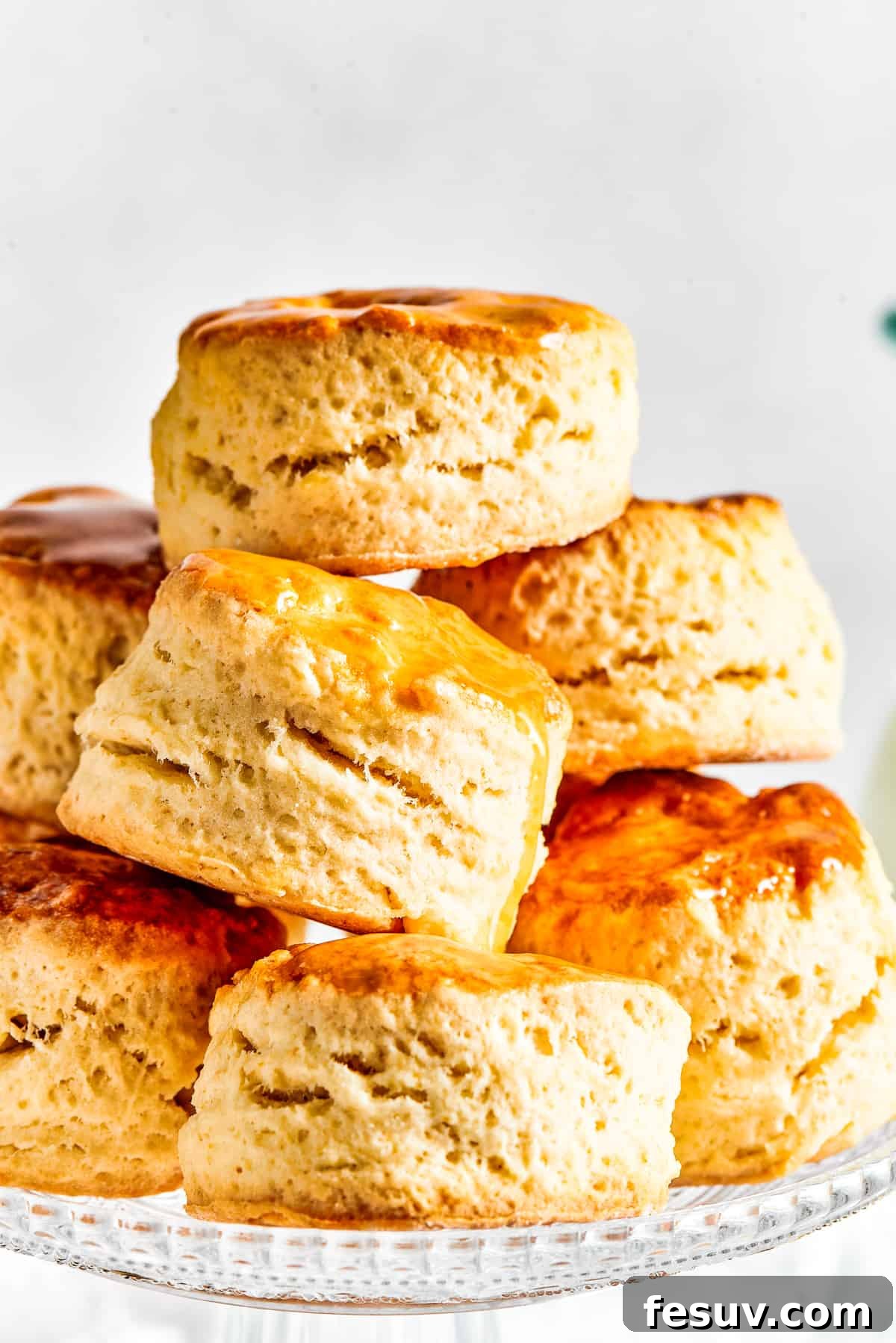 Easy Homemade Biscuits are a buttery, flaky must-have for special meals, and they are so simple to make! Fluffy, melt-in-your-mouth biscuits. A beautiful pyramid stack of six golden, perfectly risen homemade biscuits elegantly arranged on a white cake plate.