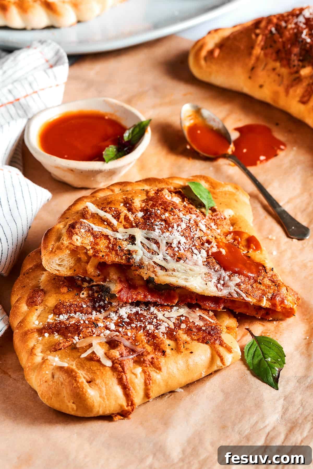 A golden-brown pizza pocket, perfectly cut in half to reveal its molten, cheesy filling with visible pepperoni and sauce.