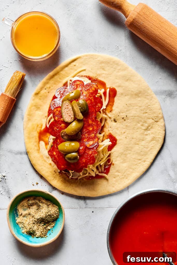 A circle of dough piled high with a thick layer of sauce, melted cheese, and various pizza toppings, ready to be folded.