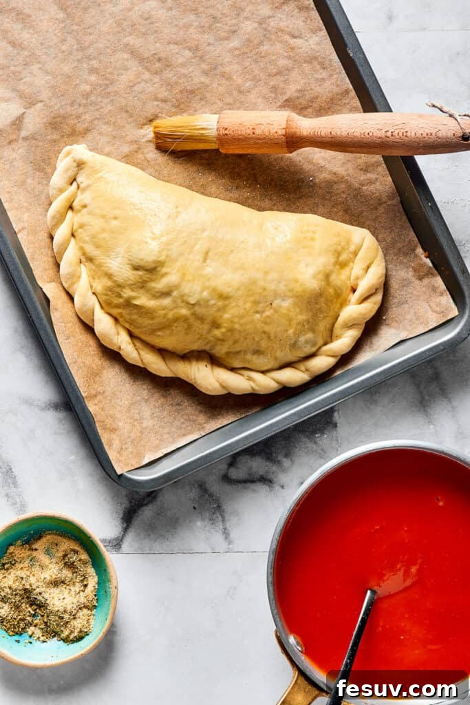 A perfectly folded calzone with neatly crimped edges, ready for its final toppings.