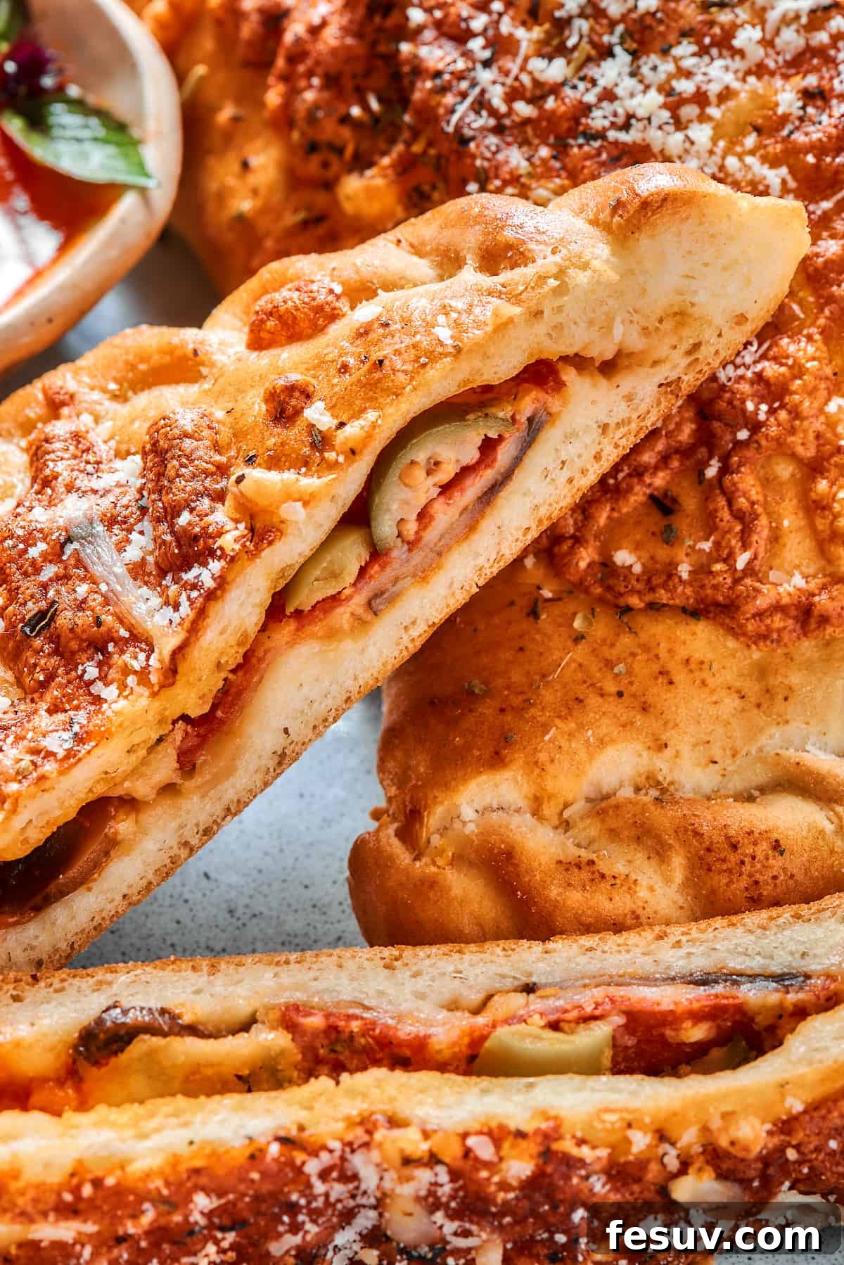 A close-up view of the perfectly cooked, cheesy interior of a halved pepperoni calzone, showcasing its rich filling.