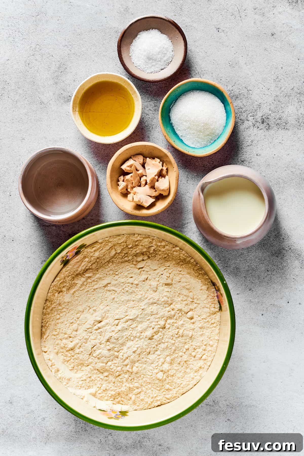 A collection of calzone dough ingredients laid out: salt, olive oil, sugar, water, yeast, milk, and flour, symbolizing the fresh, wholesome base of the recipe.