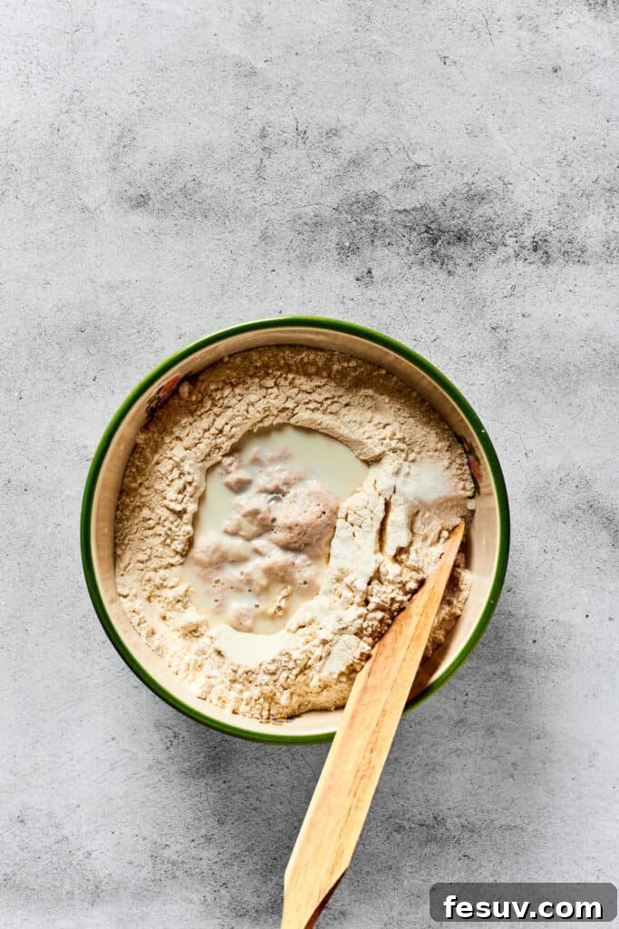 Mixing together calzone dough in a mixing bowl with a hand.