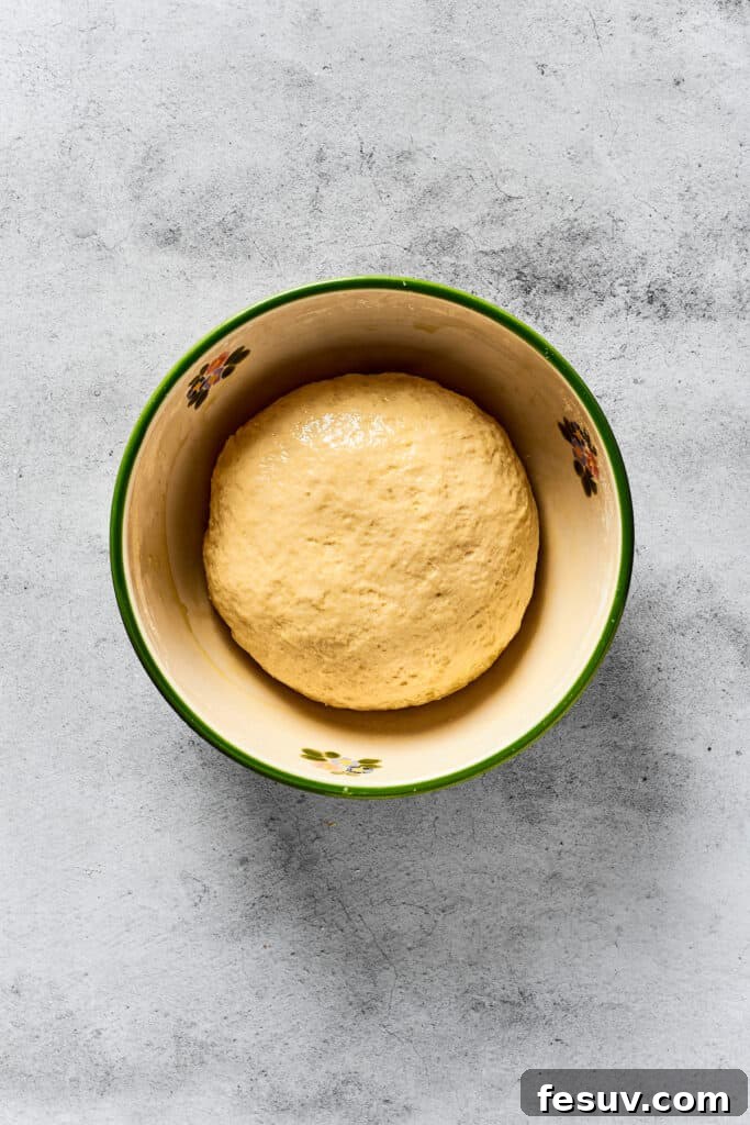 A small, smooth ball of calzone dough resting neatly in a mixing bowl.