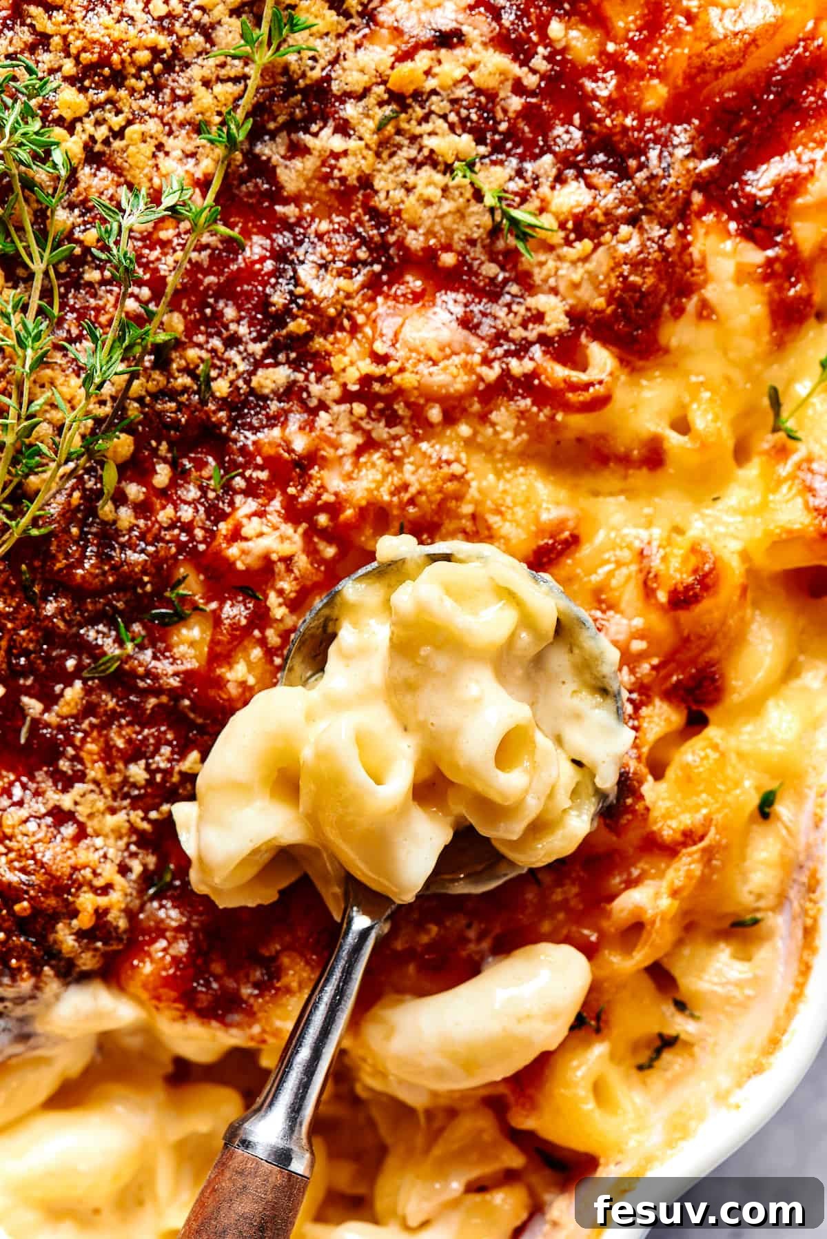 A major family favorite, this ultra-cheesy Baked Macaroni and Cheese is easy to make and perfect for holidays, meatless meals, or anytime! A generous serving of baked macaroni and cheese being scooped out of a casserole dish, showing its golden-brown, bubbly top and creamy interior.