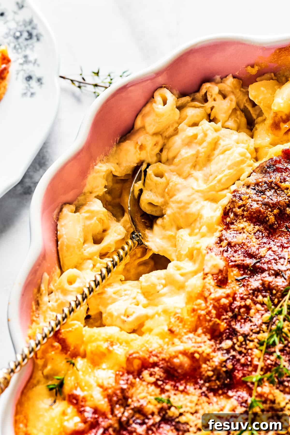 A major family favorite, this ultra-cheesy Baked Macaroni and Cheese is easy to make and perfect for holidays, meatless meals, or anytime! A close-up shot of a serving spoon scooping out a hot, cheesy portion of baked macaroni from a casserole dish, highlighting the melted cheese pull.