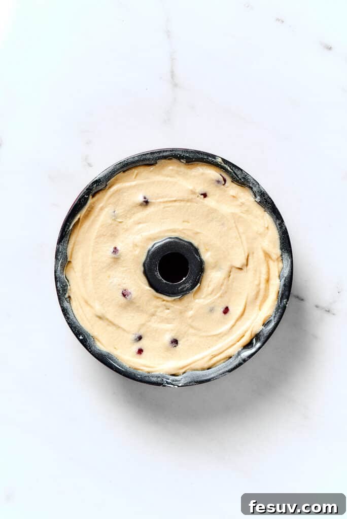 Winterberry Pound Cake Bliss 11 A close-up shot of a Bundt pan expertly filled with smooth, prepared cake batter, ready for baking.