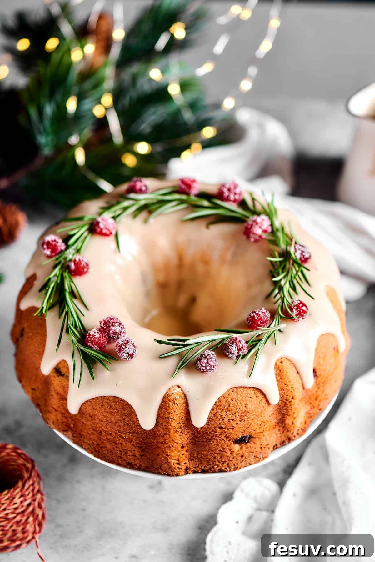 Winterberry Pound Cake Bliss 14 An inviting overhead shot of a festive Bundt cake, beautifully garnished with fresh rosemary sprigs and sparkling sugared cranberries, ready for a holiday gathering.