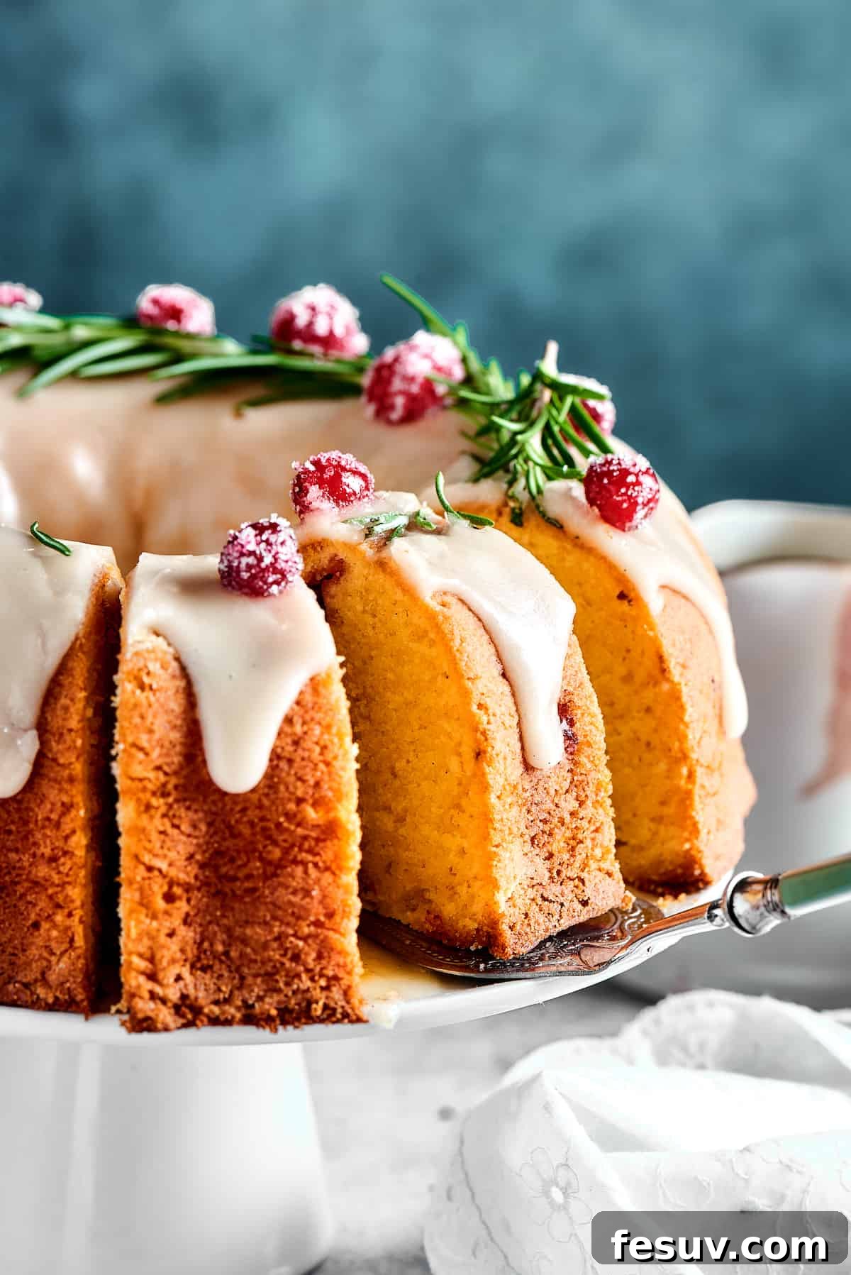 Winterberry Pound Cake Bliss 3 A whole cranberry pound cake on a cake stand, with a portion already sliced and ready to be served, highlighting its moist texture and cranberry distribution.