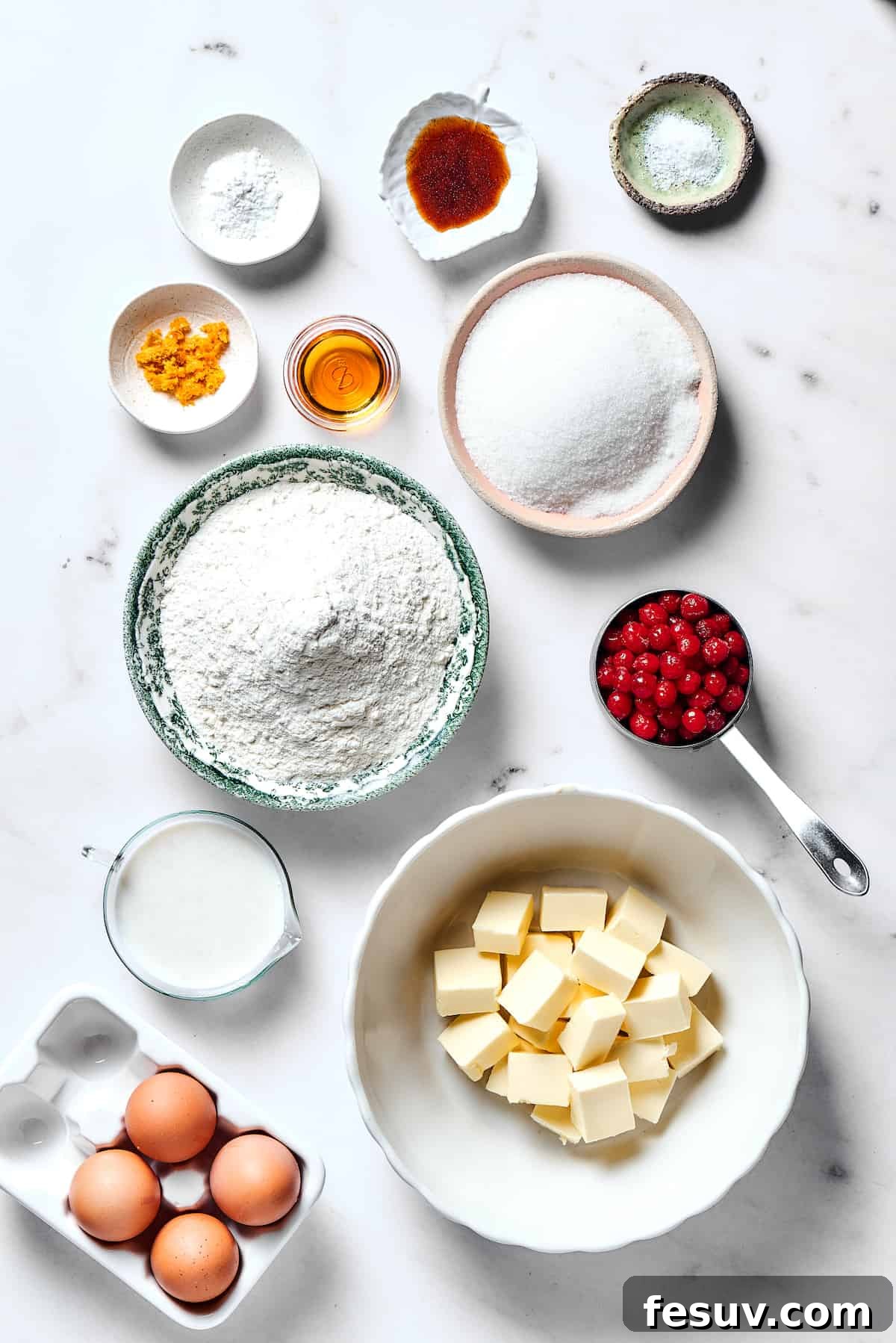 Winterberry Pound Cake Bliss 4 An overhead view showcasing all the key ingredients for Christmas Cranberry Pound Cake, neatly arranged on a rustic surface. Ingredients include baking powder, vanilla, salt, orange zest, orange liqueur, granulated sugar, all-purpose flour, fresh cranberries, buttermilk, softened butter, and eggs.