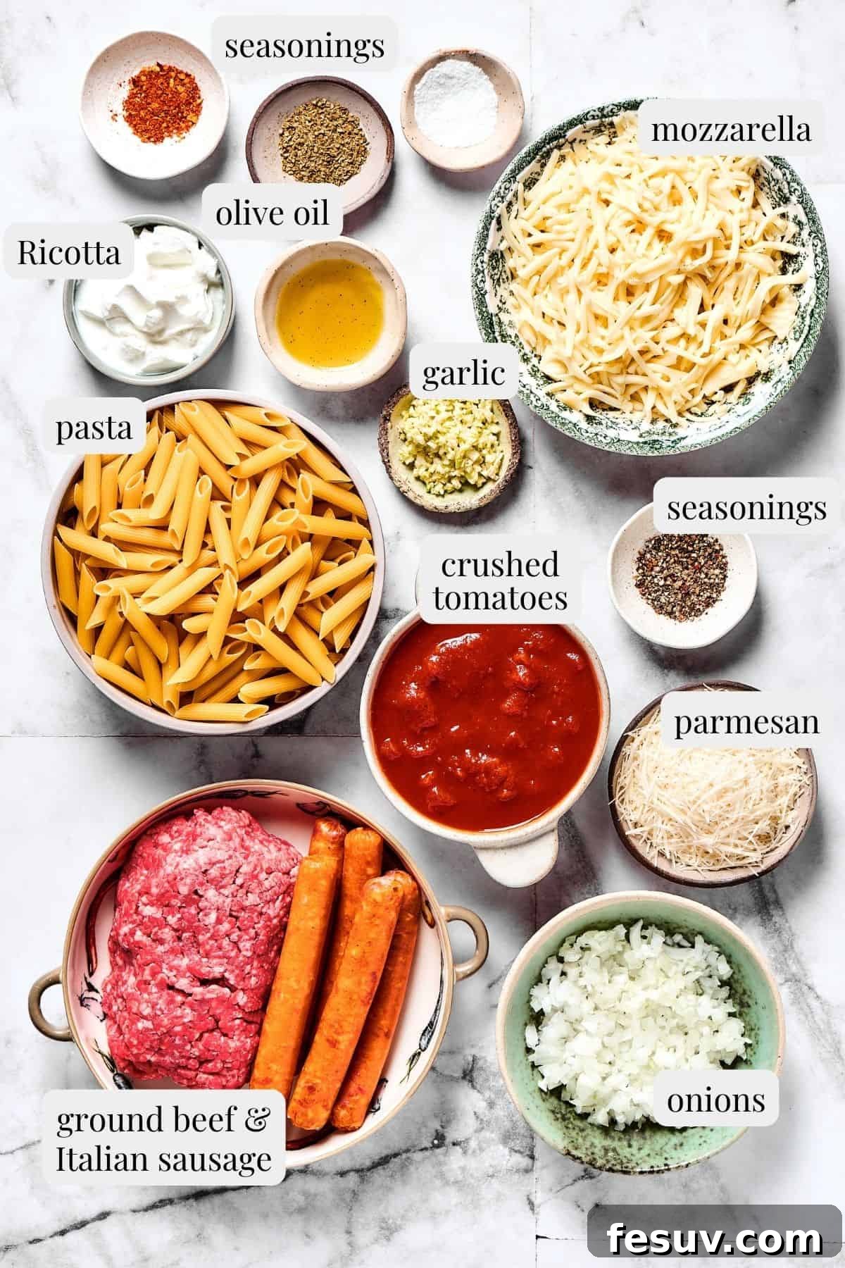 Baked Mostaccioli is a wholesome pasta dinner prepared with a homemade tomato sauce including Italian sausage, ground beef, and lots of cheese! An overhead photo showcasing all the fresh ingredients laid out for making mostaccioli, including pasta, ground meats, cheeses, and tomatoes.