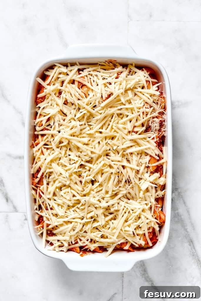 Baked Mostaccioli is a wholesome pasta dinner prepared with a homemade tomato sauce including Italian sausage, ground beef, and lots of cheese! A baking dish beautifully layered with the pasta mixture, mozzarella, and parmesan cheese, ready for the oven.