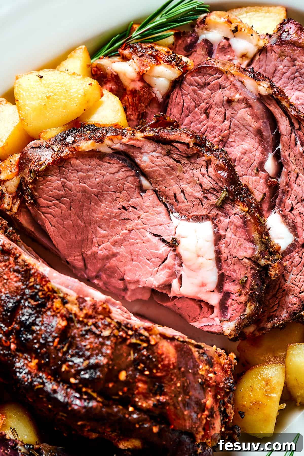 Making the perfect Prime Rib is easy! A few flavorful herbs and spices plus an easy reverse-sear roasting method are all you need. Close-up shot of prime rib, sliced and garnished with herbs.
