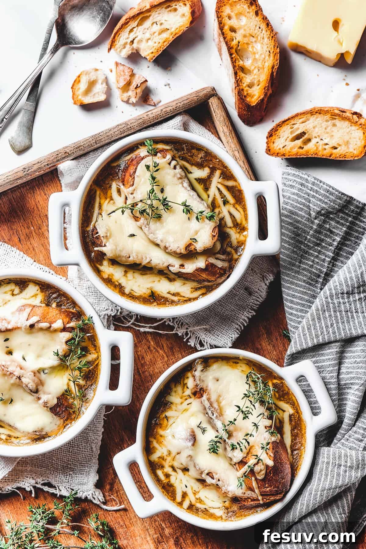 Indulge in a bowl of classic French Onion Soup, with its savory broth and irresistible cheesy topping. Individual oven-safe crocks of French onion soup, each perfectly topped with a golden-brown cheesy crouton and ready to be served.