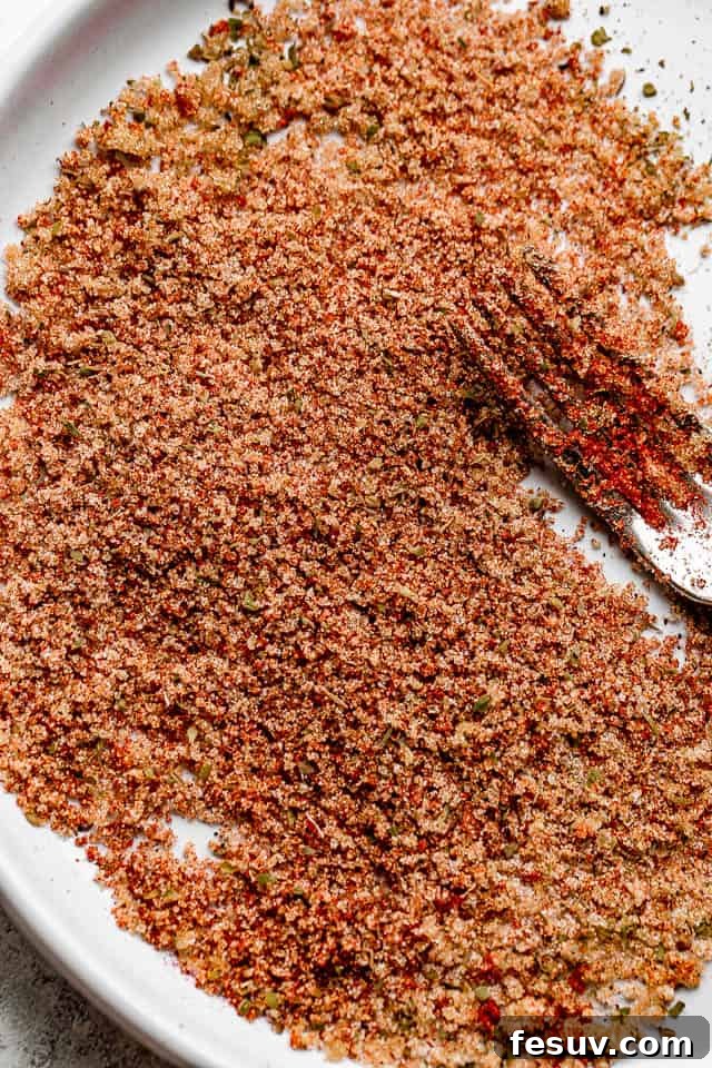 Moist, juicy & tender Cajun chicken thighs are flavorful, rich, and cooked in a spicy Cajun rub and topped with velvety butter sauce. A small bowl filled with homemade Cajun seasoning, showcasing the rich blend of spices.
