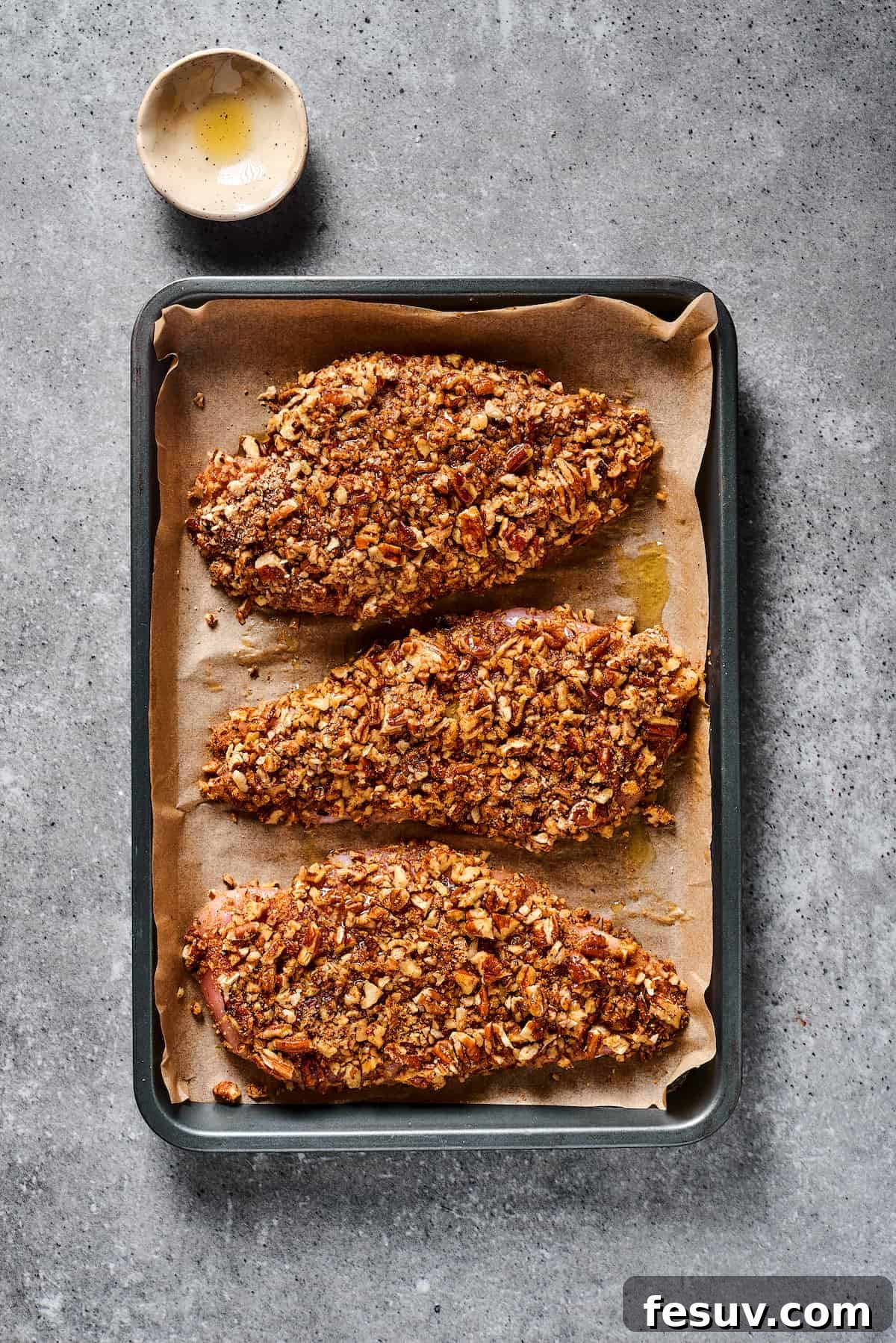 Pecan-coated chicken on a baking sheet.