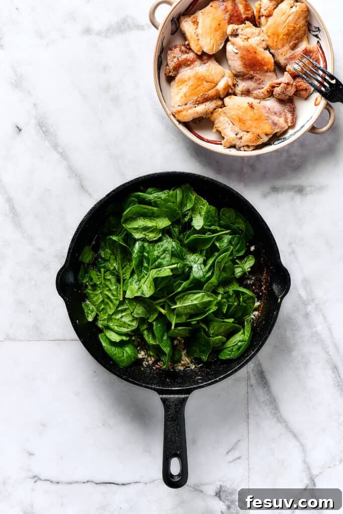 Velvety Chicken Gnocchi Delight 3 Fresh baby spinach cooking and wilting in a skillet with garlic.